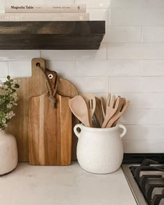 wooden utensils and cutting boards sit on the kitchen counter next to a potted plant