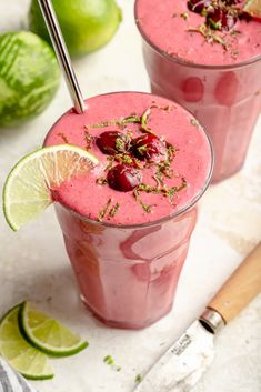 two glasses filled with smoothie and garnished with cherries next to watermelon wedges