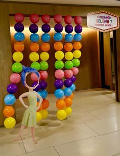 a woman standing in front of a giant number made out of balloons and streamers