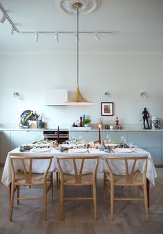 a dining room table set for four with white linens and place settings on it