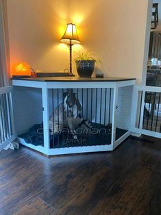 a dog is sitting in his kennel on the floor