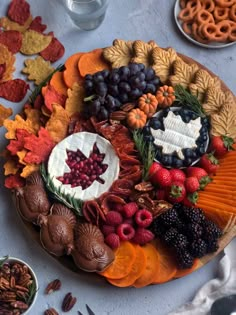 a platter filled with fruit, nuts and chocolates on top of a table