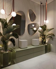 a bathroom with mirrors and planters on the counter top, along with lights hanging from the ceiling