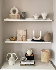 shelves with vases, pictures and other items on them in the corner of a room