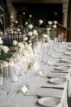 a long table is set with white flowers and place settings for an elegant dinner party