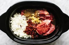 meat, rice and seasonings in a slow cooker on a marble counter top