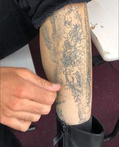 a person with a tattoo on their arm and leg is holding something in her hand