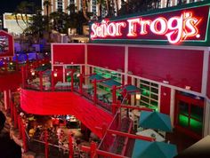 a restaurant with neon signs above it and people sitting at tables outside the restaurant area