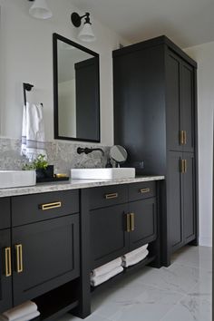 a bathroom with two sinks, mirrors and cabinets in dark gray color scheme on the wall