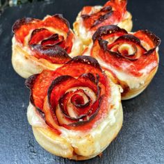 four small pastries with bacon and cheese on them sitting on a black table top