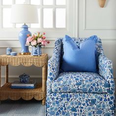 a blue and white chair sitting next to a table with flowers on it