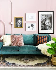 a living room with pink walls and pictures on the wall, including a green couch