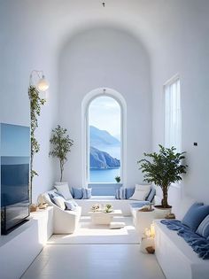 a living room filled with white furniture and a large window overlooking the ocean at night