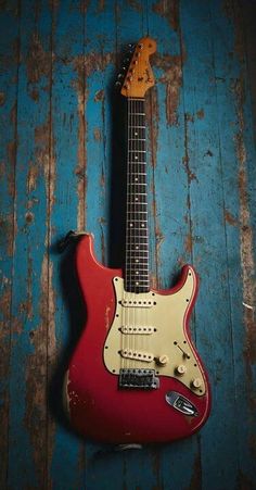 an electric guitar sitting on top of a wooden floor next to a blue and red wall