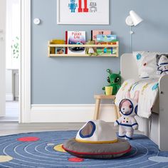 a child's bedroom with blue walls and toys on the floor in front of it