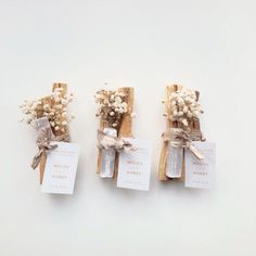 three small wooden sticks with baby's breath tied to them, each holding a card