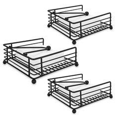 three black metal trays with wheels on each side and two white mattresses in the middle