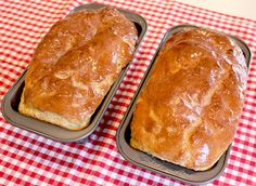 two loafs of bread sitting on top of a red and white checkered table cloth