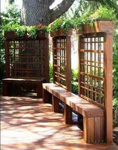 a wooden bench sitting under a tree on top of a hard wood floored walkway