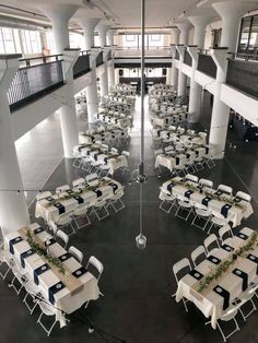 tables and chairs are set up in the middle of an indoor space with high ceilings