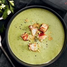 a bowl filled with green soup and garnished with croutons on top