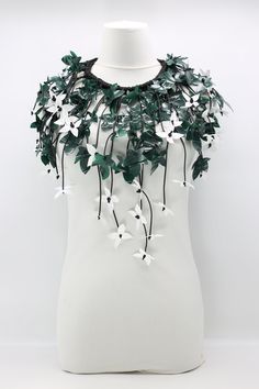 a white mannequin with green and white flowers on it's neckline