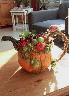 a pumpkin decorated with berries, leaves and other decorations on a table in a living room