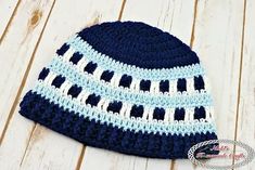 a blue and white crocheted hat sitting on top of a wooden floor