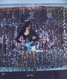 a woman standing in front of a wall covered with confetti