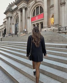 a woman walking up some steps in front of a building