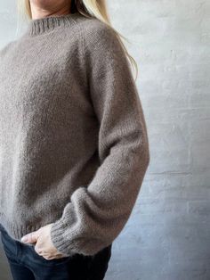 a blonde woman wearing a gray sweater and jeans