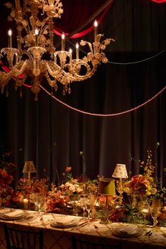 a dining room table is set with candles, flowers and place settings for an elegant dinner