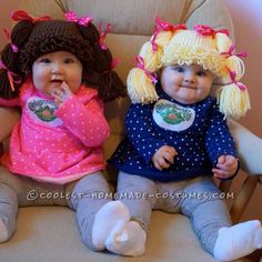 two baby dolls sitting next to each other on a chair