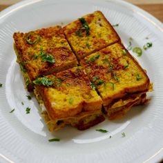 four pieces of bread on a white plate with parsley sprinkled around the edges