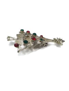 1971 vintage holiday brooch pin. This fancy figural Christmas tree brooch is made by Corel. It is silver tone and jeweled with Ruby Red, Emerald Green and Crystal Clear Rhinestones. Corel Hallmark. This Hallmark was only used in 1971. Nice accessory for the holiday Christmas holiday season. DETAILS: ☼ Approximately 2 3/8 by 1 1/2 inches. ☼ Approximately 10.6 grams total weight. ☼ ☼ ☼ ☼ ☼ ☼ ☼ ☼ ☼ ☼ ☼ ☼ ☼ ☼ ☼ ☼ ☼ ☼ ☼ ☼ ☼ PLEASE NOTE: ☼ Different items on SALE everyday! Check back often to take adv Silver Brooches For Christmas Party, Silver Christmas Party Brooches, Silver Christmas Party Brooch, Vintage Christmas Brooches, Vintage Red Brooches For Festive Occasion, Vintage Holiday, Rose Earrings, Ruby Red, Flower Brooch