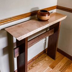 a wooden table with a bowl sitting on it's top next to a wall