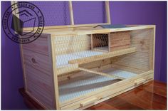 a chicken coop with the door open on top of a wooden table in front of purple wall