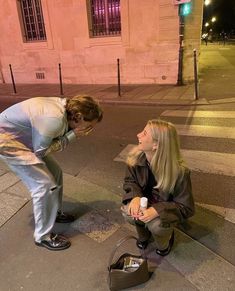 a man kneeling down next to a woman on the street