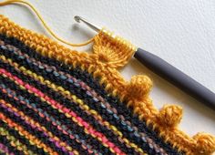 a crocheted piece of yarn with a knitting needle on the side next to it