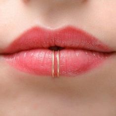 a woman's lips with two gold rings on her lip