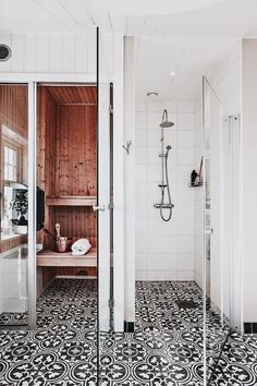 a bathroom with black and white flooring and wooden paneled walls, along with a walk in shower