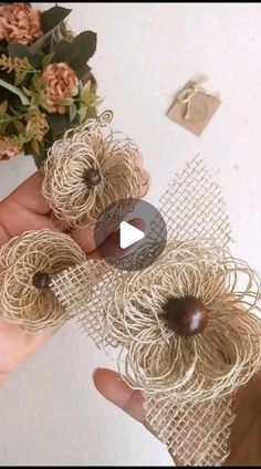 someone is holding some twine balls with flowers in the background and video recording them