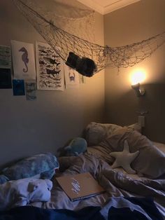 an unmade bed with a laptop on top of it and some pictures hanging from the ceiling