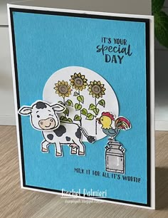 a card with a cow and sunflowers next to a vase filled with flowers