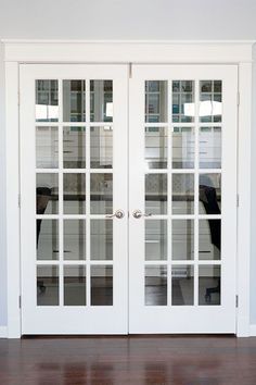 an empty room with two white doors and hard wood flooring in front of it