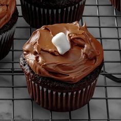 chocolate cupcakes with frosting and marshmallows on a cooling rack