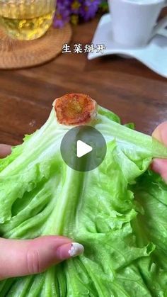 a person holding lettuce in their hands with a piece of meat on it