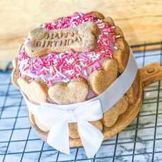 a cake with pink sprinkles and white frosting is on a cooling rack