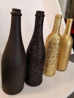 three black and gold vases sitting on top of a white shelf next to each other