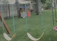 two swings are in the grass next to a child's swing set